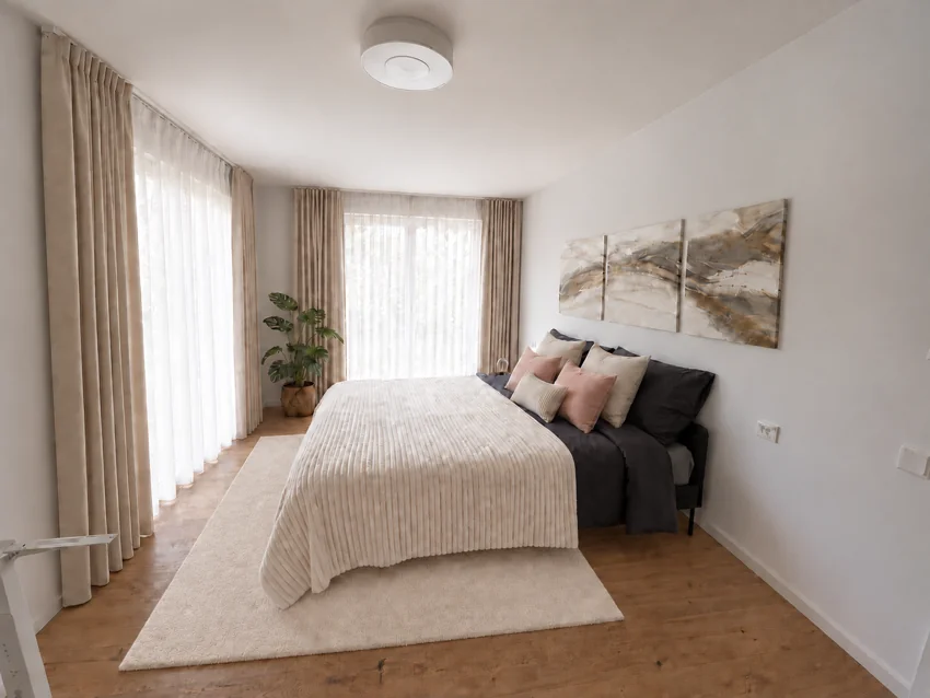 Chambre lumineuse avec textiles crème et rideaux devant deux portes-fenêtres