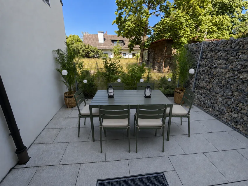 Terrasse avec une table dressée pour six personnes devant le jardin verdoyant