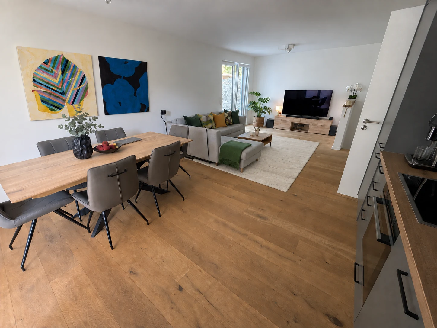 Séjour ouvert avec parquet, table à manger en bois et grand canapé
